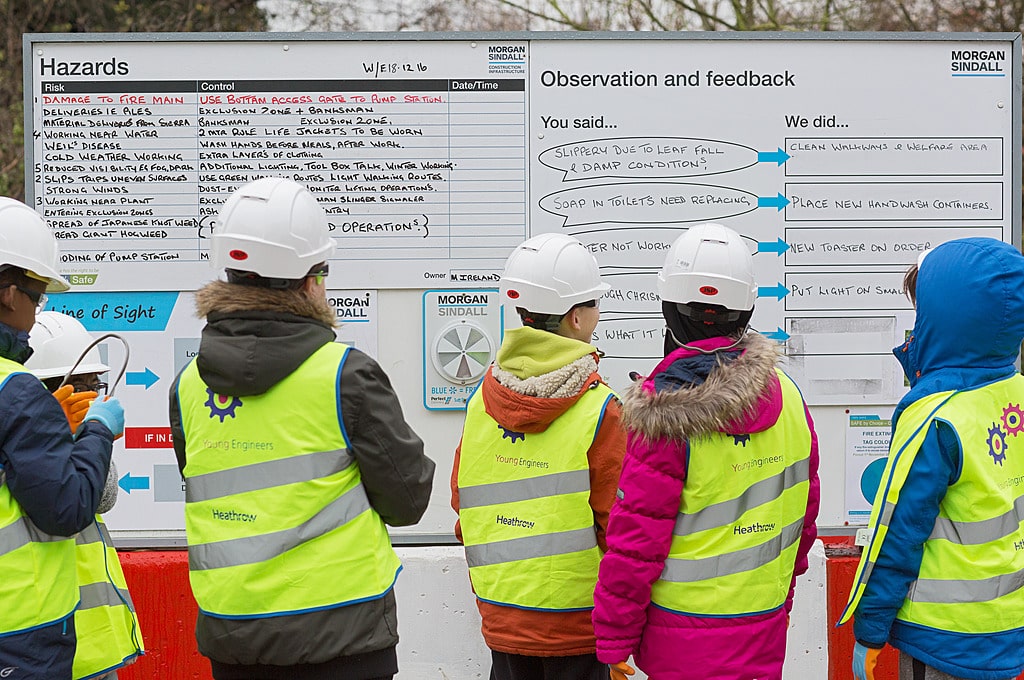 people in hard hats and high visiblity vests at white board